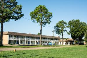 a building with a tree in front of it at Motel 6-Brinkley, AR in Brinkley