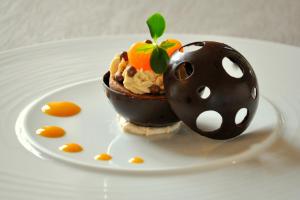 a chocolate dessert with an orange on top on a plate at Logis Hôtel Le Moulin de Chalons in Le Gua