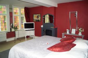 a red bedroom with a bed and a mirror at B&B Next Door in Bruges
