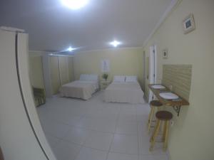 Vistas a una habitación con 2 camas y una mesa en Flat Arraial, en Arraial do Cabo