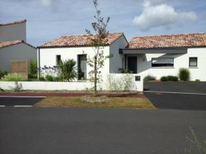 a white house with a tree in the street at Le Temps d'une Pause in Bretignolles-sur-Mer