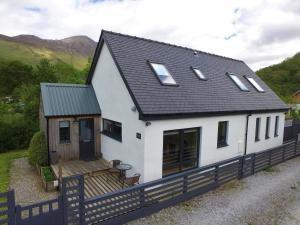 una casa blanca con techo negro en Hawthorn Cottage en Glencoe