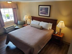 um quarto de hotel com uma cama e uma cadeira e uma janela em Colonial House Motel em Pigeon Forge