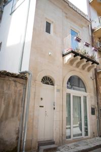 ein Gebäude mit einer weißen Tür und einem Balkon in der Unterkunft Rifugio Ibleo in Ragusa