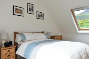 a bedroom with a white bed and a window at Hawthorn Cottage in Glencoe