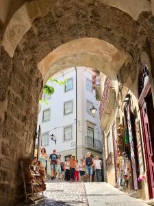 Un groupe de personnes marchant à travers une arcade dans un bâtiment dans l'établissement Change The World Hostels - Coimbra - Almedina, à Coimbra