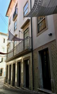 um edifício com uma varanda e um guarda-chuva numa rua em Change The World Hostels - Coimbra - Almedina em Coimbra