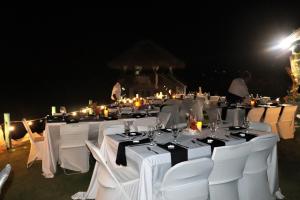 un grupo de mesas con sillas blancas por la noche en Luna Sea Inn, en Bluefields