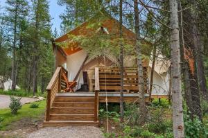 Ein Baumhaus im Wald mit Veranda und Treppe in der Unterkunft Under Canvas Glacier in Coram
