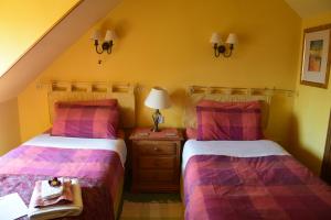 a bedroom with two beds and a table with a lamp at Sunflower Bed & Breakfast in Findhorn