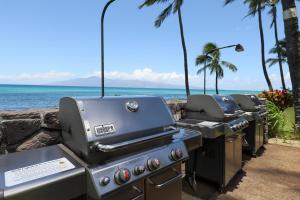 a row of grill and bbq equipment next to the ocean at Mahina Surf 109 in Kahana