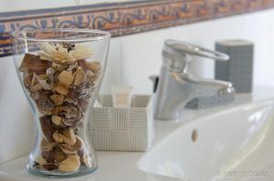 un vaso di vetro pieno di conchiglie su un lavandino del bagno di Le Dimax a Sant'Agnello Altre 27 foto