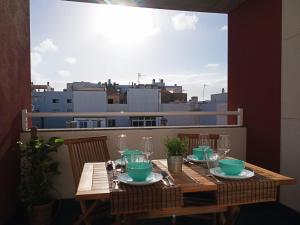 a wooden table with plates and glasses on a balcony at ATICO VIEW NATURE CORRALEJO in Corralejo