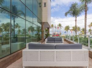 a view of a building with a couch and palm trees at Nord Luxxor Tambaú in João Pessoa