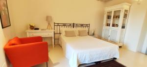 um quarto com uma cama branca e uma cadeira vermelha em Casa Carmela em Ceglie Messapica