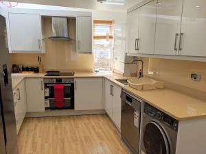 a kitchen with white cabinets and a washer and dryer at Spacious 2-bed apartment in central Kingston near Richmond Park in Kingston upon Thames