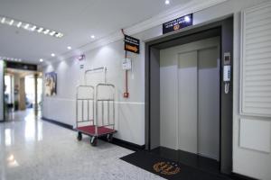 a hospital hallway with a door and a luggage cart at Hotel São Vicente in Passo Fundo