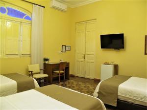 a hotel room with two beds and a desk and a television at Gran Hotel del Paraguay in Asunción