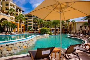 a pool at a resort with chairs and an umbrella at Casa Dorada Los Cabos Resort & Spa in Cabo San Lucas