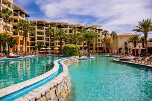 a swimming pool at a resort with chairs and palm trees at Casa Dorada Los Cabos Resort & Spa in Cabo San Lucas