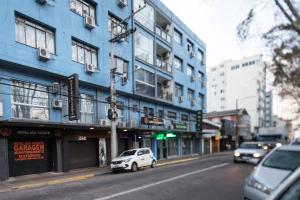 a white car parked in front of a blue building at Hotel São Vicente in Passo Fundo