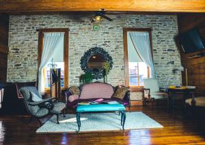 a living room with chairs and a stone wall at Upstairs Inn in Hico