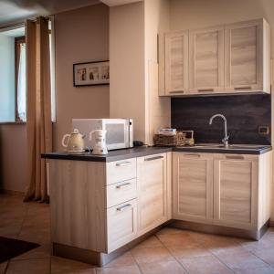 a kitchen with white cabinets and a sink and a microwave at CASA RAMAGIO' in La Morra