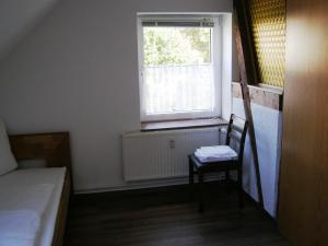 ein kleines Zimmer mit einem Stuhl und einem Fenster in der Unterkunft Hotel Alt Vinnhorst in Hannover