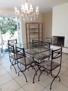 a glass table with four chairs and a chandelier at Les cerisiers in Bernardswiller