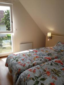 a bedroom with a bed with a floral comforter and a window at Les cerisiers in Bernardswiller