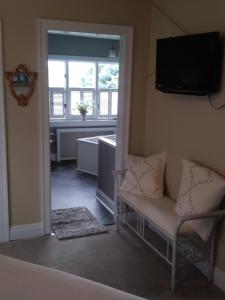 a living room with a chair and a television on the wall at The guest house at the regina house tea room in Moosic