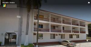 a large white building with a car parked in front of it at CONDOMINIO SÁBALO VISTA in Mazatlán