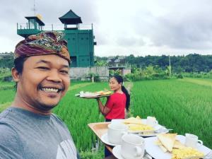 un homme tenant un plateau de nourriture avec une femme dans un champ dans l'établissement GumiBali Villa, à Tirtagangga