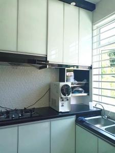 uma cozinha com armários brancos e um micro-ondas no balcão em NRL's Cozy Guesthouse em Kota Bharu