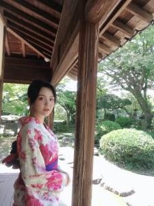 kobieta w kimono stojąca pod gankiem w obiekcie Guesthouse RETURN w mieście Kitsuki