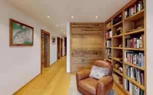 een kamer met een bibliotheek met een stoel en boekenplanken bij Polo in St. Moritz