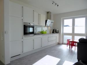 uma cozinha branca com armários brancos e uma mesa em Apartment HEIMATHAFEN, Am Alten Deich 14/1 em Dangast