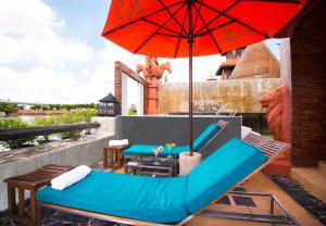 een terras met een blauwe bank en een parasol bij Ammata Lanta Resort in Lat Krabang