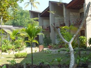 a garden in front of a building with palm trees at Pleasant View Resort in Ngapali