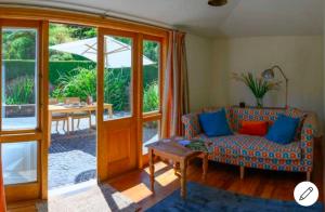 ein Wohnzimmer mit einem Sofa und einem Tisch mit einem Sonnenschirm in der Unterkunft Gate Keepers Cottage in Akaroa