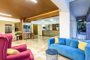 a living room with a blue couch and two pink chairs at Eurohotel Katrin Hotel & Bungalows in Stalida