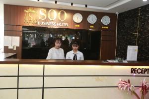 two people standing at the counter of a business hotel at Soo Hotel Bac Ninh in Bắc Ninh