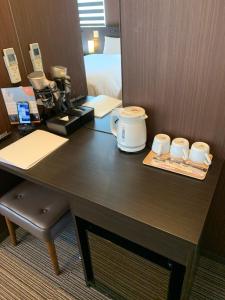 a desk with a coffee maker and two cups on it at Hotel Kojan in Osaka