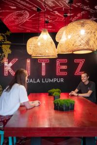 un hombre y una mujer sentados en una mesa en un restaurante en Kitez Hotel & Bunkz en Kuala Lumpur