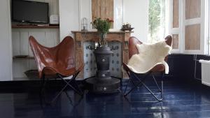 a living room with two chairs and a stove at Riley's cottage in Hemrik