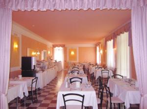 マルチェージネにあるHotel Dianaの白いテーブルクロスが敷かれたテーブルが並ぶ部屋