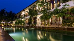 una piscina frente a un edificio por la noche en Montra Nivesha Residence, en Siem Reap