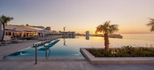 - une piscine avec des palmiers et l'océan dans l'établissement Lindos Grand Resort & Spa - Adults Only, à Lindos