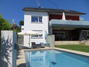 ein Haus mit einem Pool mit zwei Stühlen und einem Sonnenschirm in der Unterkunft Gästehaus Sommertal in Meersburg