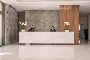 two people sitting at a reception desk in a lobby at Lindos Grand Resort & Spa - Adults Only in Líndos